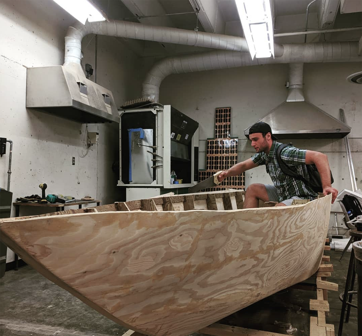 photo of male student working on wooden solar splash boat